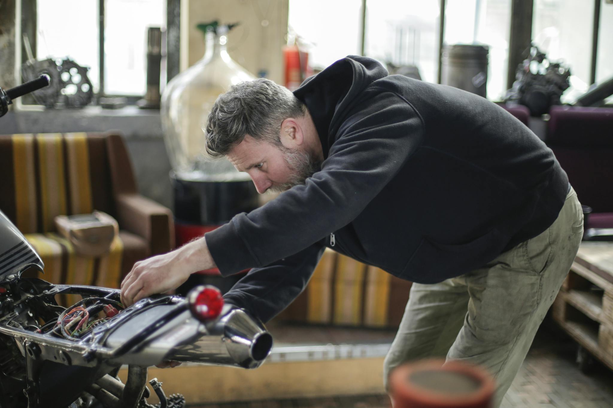 A focused mechanic works on a motorcycle inside a spacious workshop.