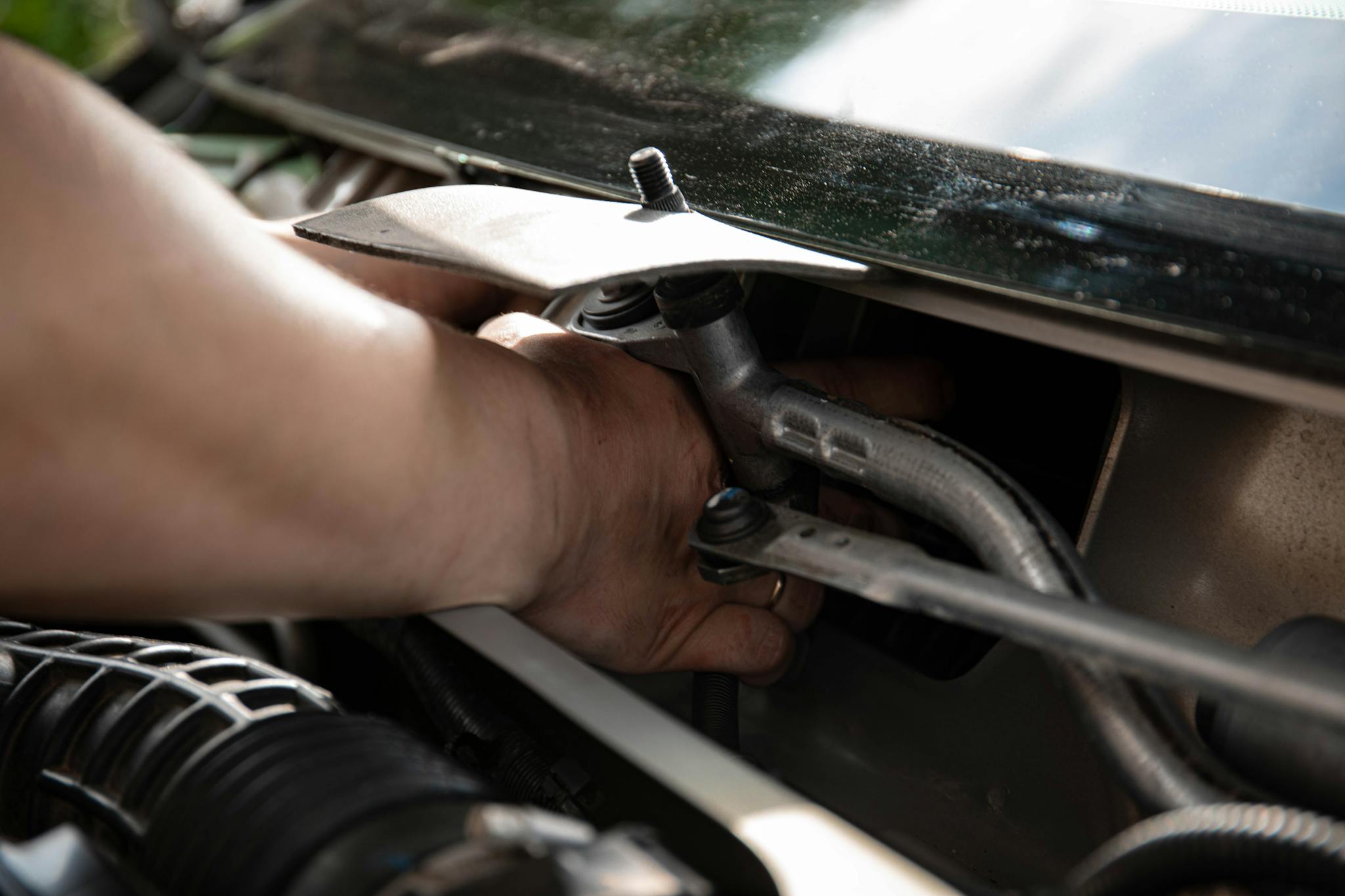 Close-up of a mechanic's hands working on car engine maintenance.