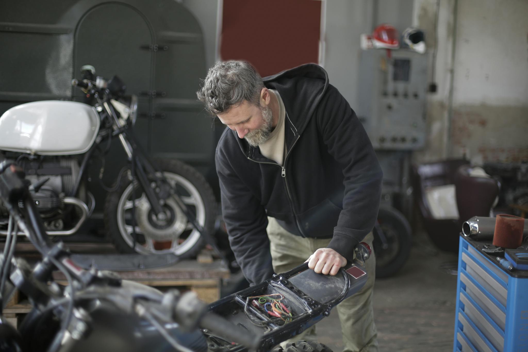 Mechanic in workshop fixing a motorbike, focusing on diagnostics and repair.
